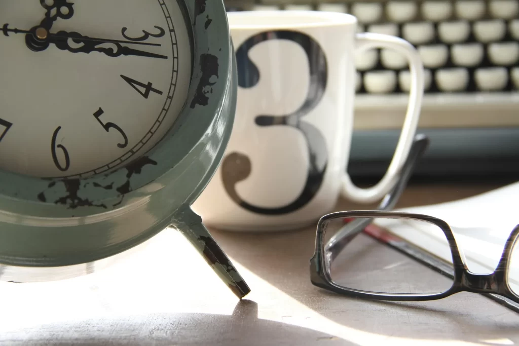 Klok, bril en werkplek als symbool voor timemanagement en een slimme indeling van je werkweek.